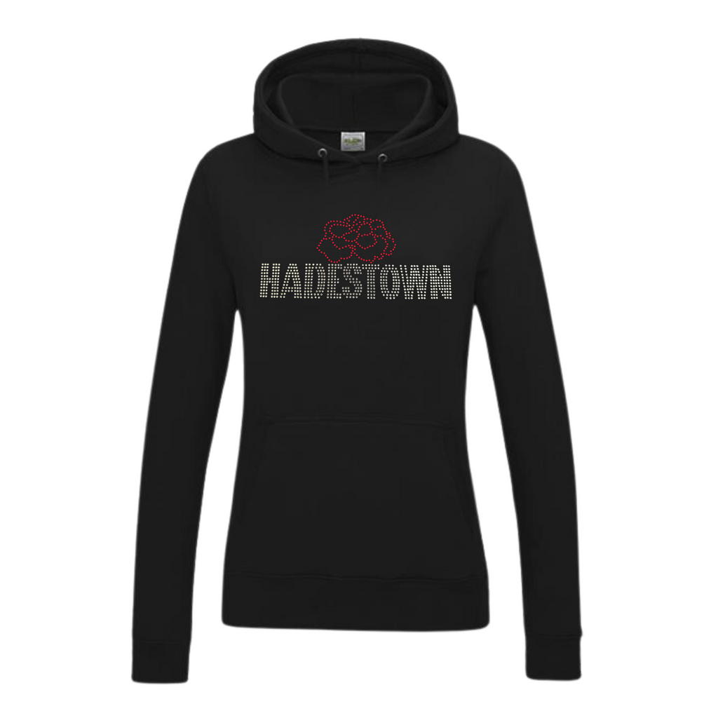 Black pullover hoodie with front kangaroo pocket, on the front there is silver HADESTOWN lettering in capitals, there is then a red carnation flower design resting on the middle of the lettering
The design is made up of sparkling rhinestones that catch the light
