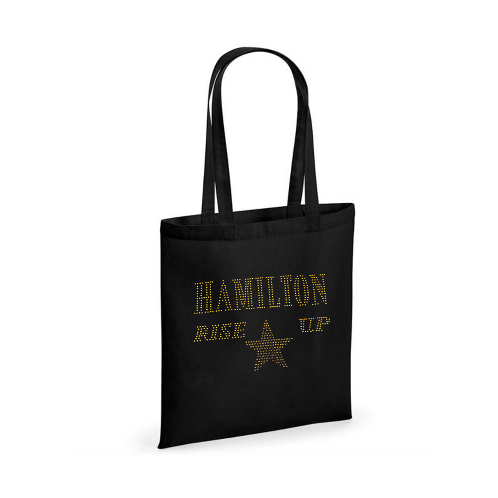 Black cotton tote bag, on the front is a gold sparkling "Hamilton Rose up" lettering with a gold star set just underneath.
design is made up of sparkling rhinestones that catch the light beautifully