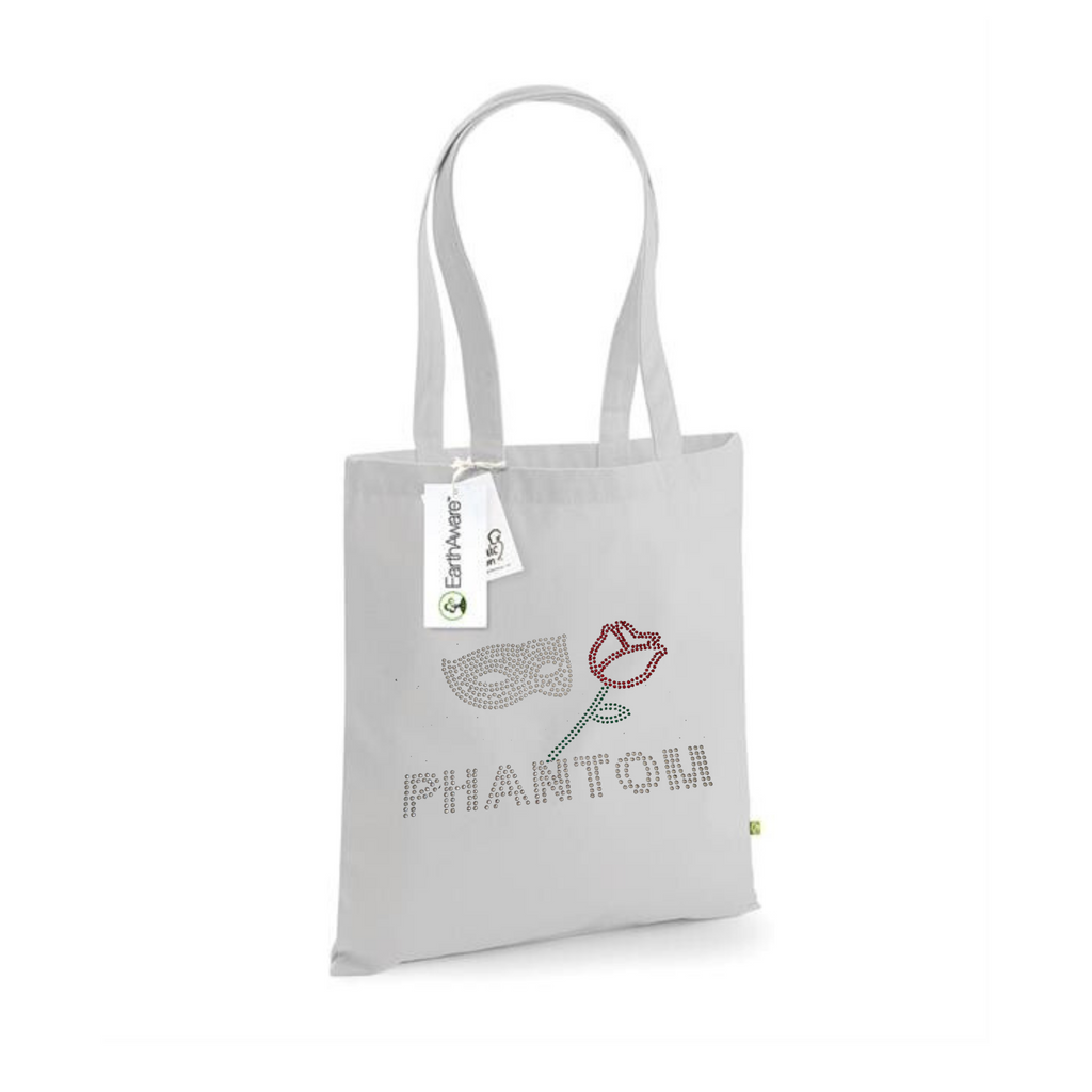 LIGHT GREY COTTON TOTE BAG WITH LONG HANDLES WITH PHANTOM LETTERING, ABOVE THIS A SILVER MASK AND RED ROSE WITH GREEN STEM AND LEAF.
THE DESIGN IS MADE UP OF HOT FIX RHINESTONES THAT HEAT PRESSED AND CATCH THE LIGHT BEAUTIFULLY