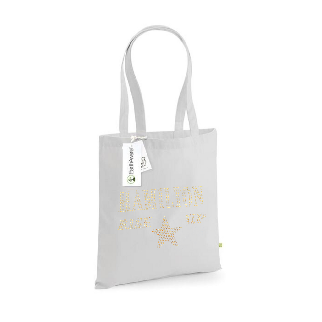 Light grey cotton tote bag, on the front is a gold sparkling "Hamilton Rose up" lettering with a gold star set just underneath.
design is made up of sparkling rhinestones that catch the light beautifully